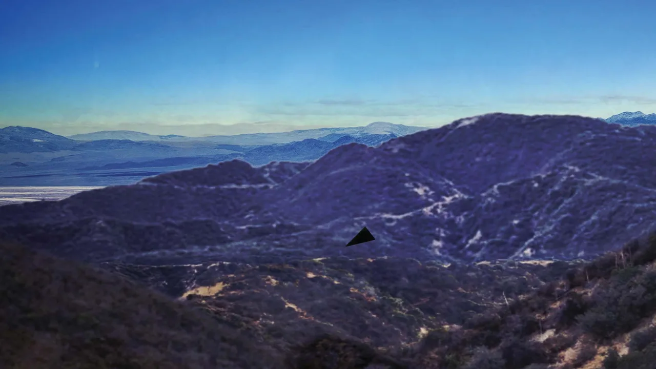 Blue-tinted photo of brush-covered mountain ridges under a clear sky, with a small black triangle pasted into the scene above a canyon to show where witnesses placed the object